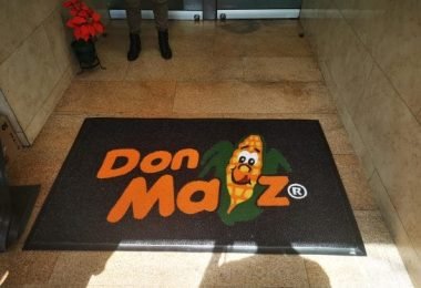 Tapete atrapamugre con personaje de Don Maz en entrada de edificio.