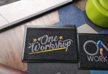 Alfombra atrapamugre para oficina con mensaje "One Workshop" y diseño colorido.